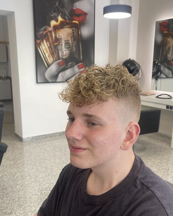 Junger Kunde mit lockiger Deckhaarpartie und kurzen Seiten