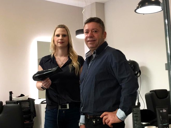 Das Team des Friseursalons IBO im Spiegel des Salons, eine Mitarbeiterin mit Föhn in der Hand neben ihrem Kollegen